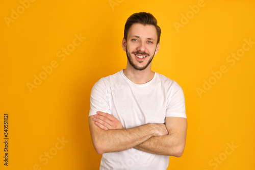 A portrait of handsome man in in white t-shirt crossing hands.
