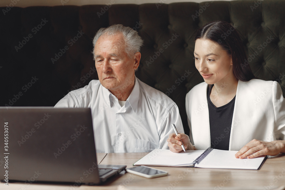 Senior with a young assistant. Businessman working in the cafe. Man in a white shirt. Young woman with her boss. Senior with a young assistant. Businessman working in the cafe. Man in a white shirt. Young woman with her boss.