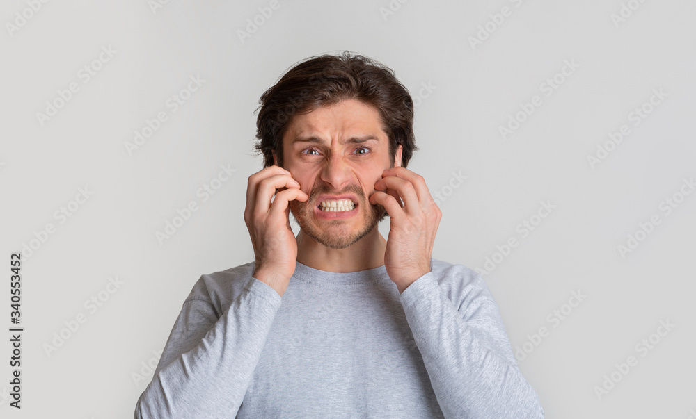 Allergy concept. Millennial man scratches his cheeks Allergy concept. Millennial man scratches his cheeks
