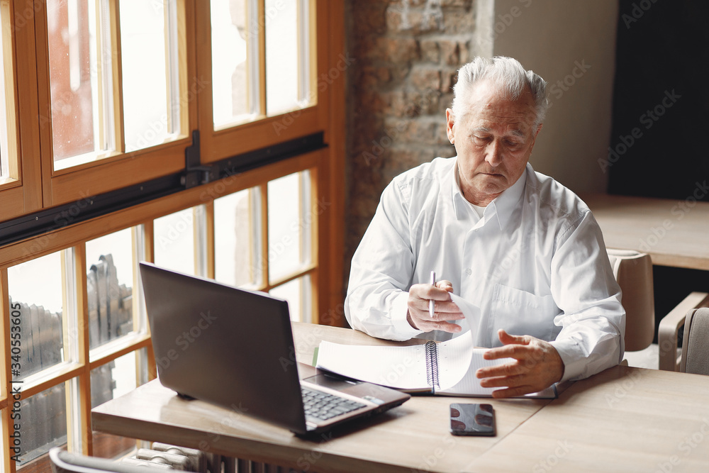 Senior with a laptop. Businessman working in the cafe. Man in a white shirt. Senior with a laptop. Businessman working in the cafe. Man in a white shirt.
