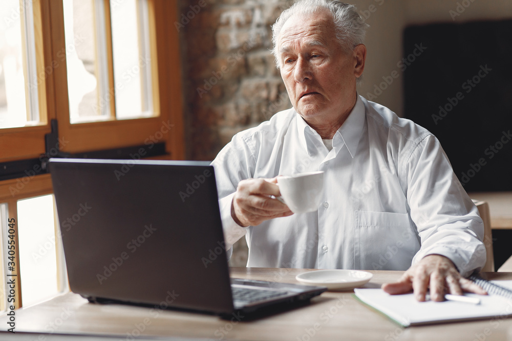 Senior with a laptop. Businessman working in the cafe. Man in a white shirt. Senior with a laptop. Businessman working in the cafe. Man in a white shirt.