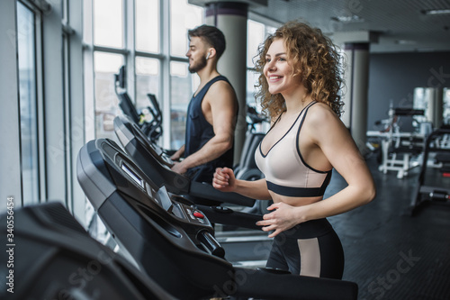 Young sports couple making cardio workout in modern gym