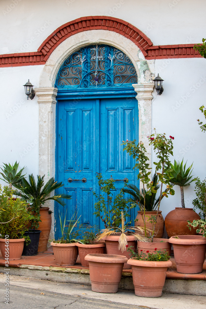 beautiful old blue door with lots of ceramic pots with plants in traditional villages of Cyprus and the Mediterranean