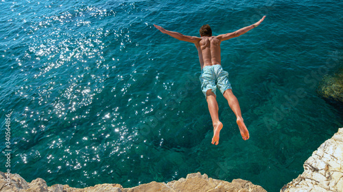 COPY SPACE: Young man on a summer vacation does cliff diving on a sunny day.