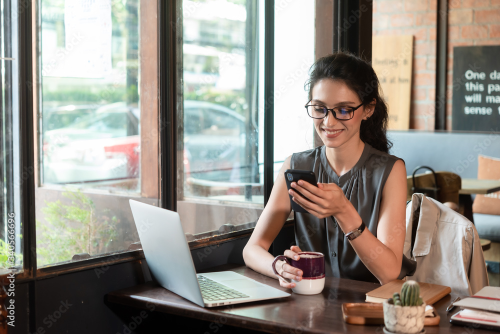 Beautiful woman have coffee in cafe while work in morning freelance, nomad work style use smartphone Beautiful woman have coffee in cafe while work in morning freelance, nomad work style use smartphone