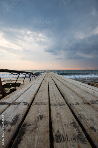 wooden bridges leading out to the sea at sunset, dark sky before a thunderstorm, a place for fishing and meditation