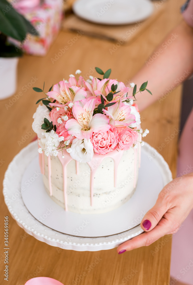 beautiful cake with flowers on a white stand in women's hands beautiful cake with flowers on a white stand in women's hands
