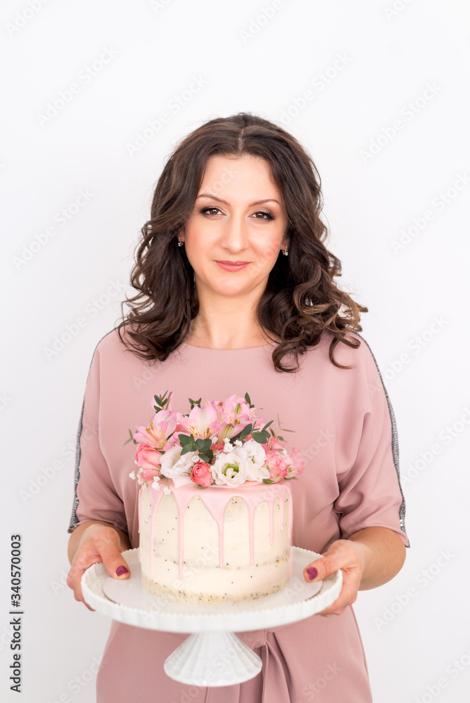 female pastry chef holds a cake decorated with flowers on a white background female pastry chef holds a cake decorated with flowers on a white background