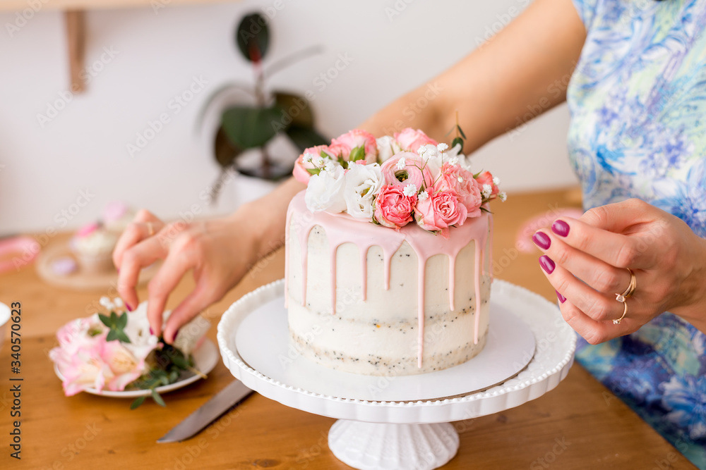 close-up of women's hands decorating the cake with fresh flowers.. close-up of women's hands decorating the cake with fresh flowers..