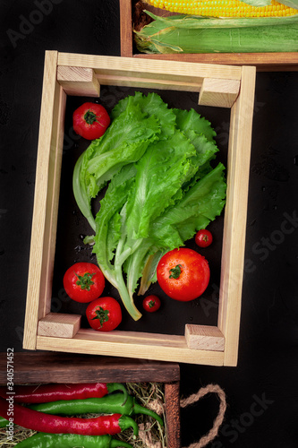 Wooden box with fresh vegetables inside on black background