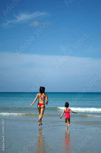 Asian chinese woman spending time playing with daughter at the beach