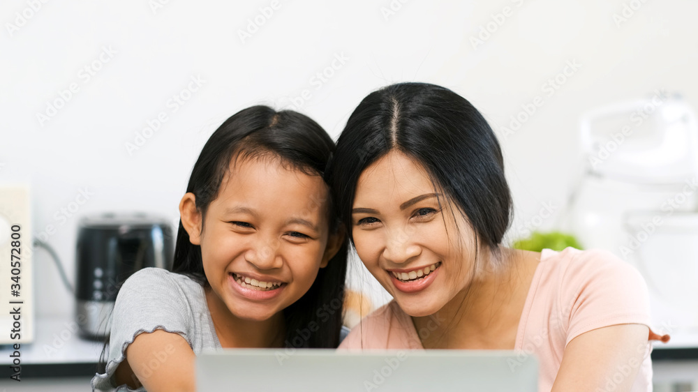Mother and preteen daughter video call to grandparent in kitchen at home.family happy time.video conference with laptop.quarantine activity when outbreak of coronavirus.e-learning concept - obrazy, fototapety, plakaty 