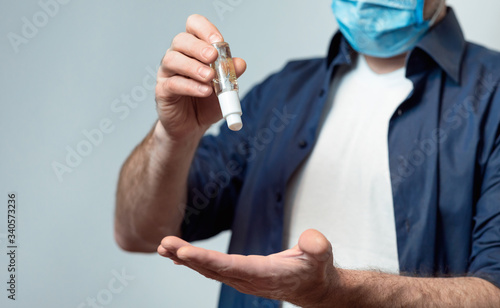 Unrecognizable Man Disinfecting Hands With Sanitizer Over Gray Background, Cropped