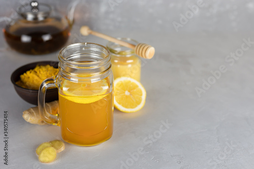 Vitamin useful tea and ingredients for its preparation: ground turmeric, honey, ginger root, lemon on a gray background.