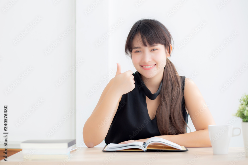 Beautiful portrait young asian woman smiling sitting study and learning writing notebook and diary in the living room at home, girl homework, business woman working on table, education concept. Beautiful portrait young asian woman smiling sitting study and learning writing notebook and diary in the living room at home, girl homework, business woman working on table, education concept.