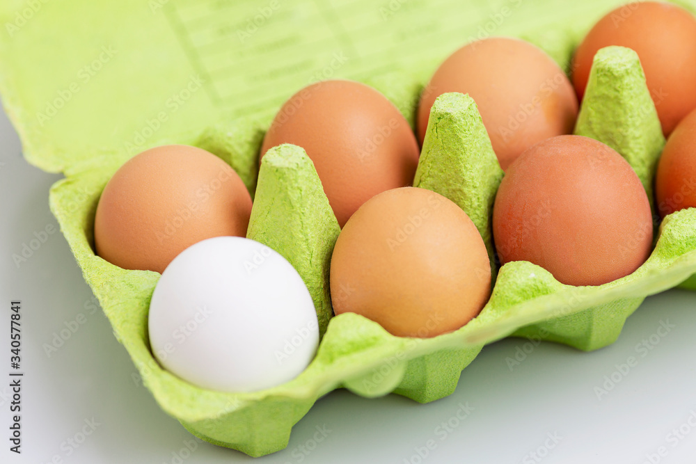 Cinnamon and one white chicken egg in an eco-green green paper container. Healthy diet food. Close-up. White background. Cinnamon and one white chicken egg in an eco-green green paper container. Healthy diet food. Close-up. White background.