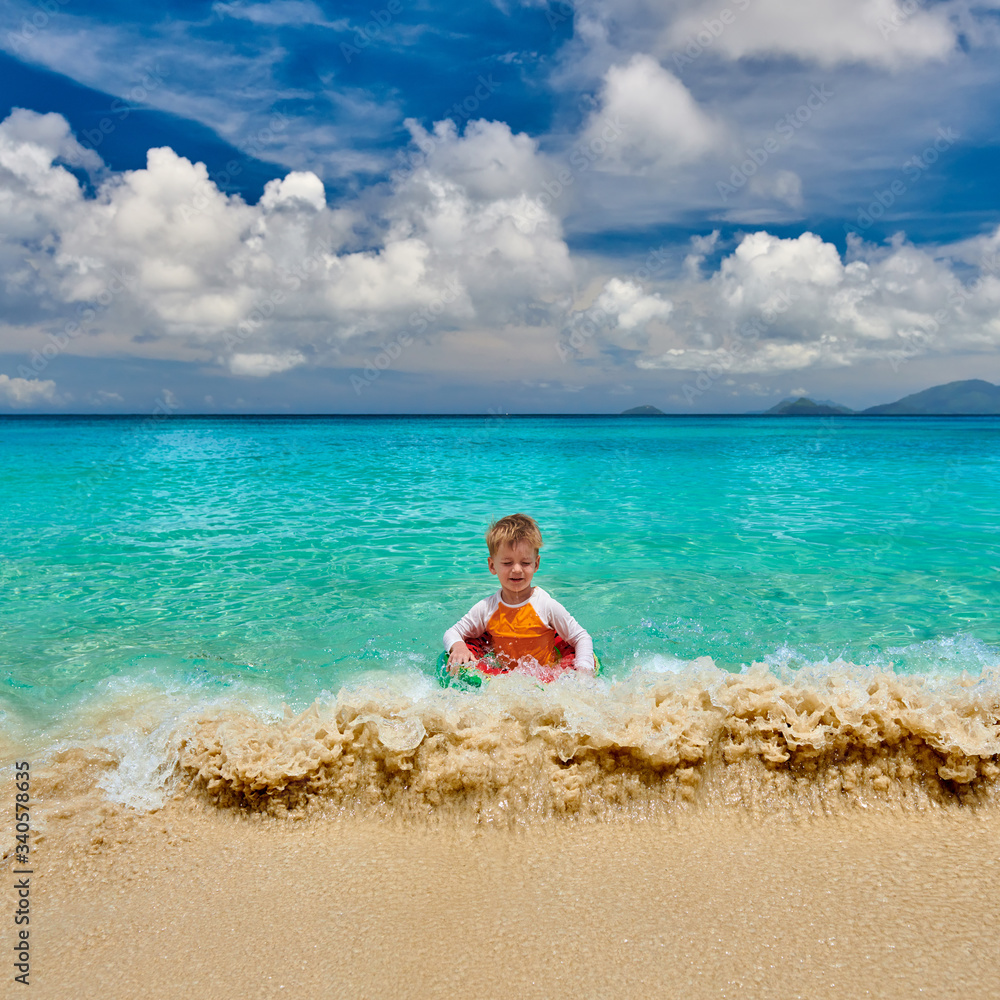 Toddler boy on beach swimming with inflatable ring Toddler boy on beach swimming with inflatable ring