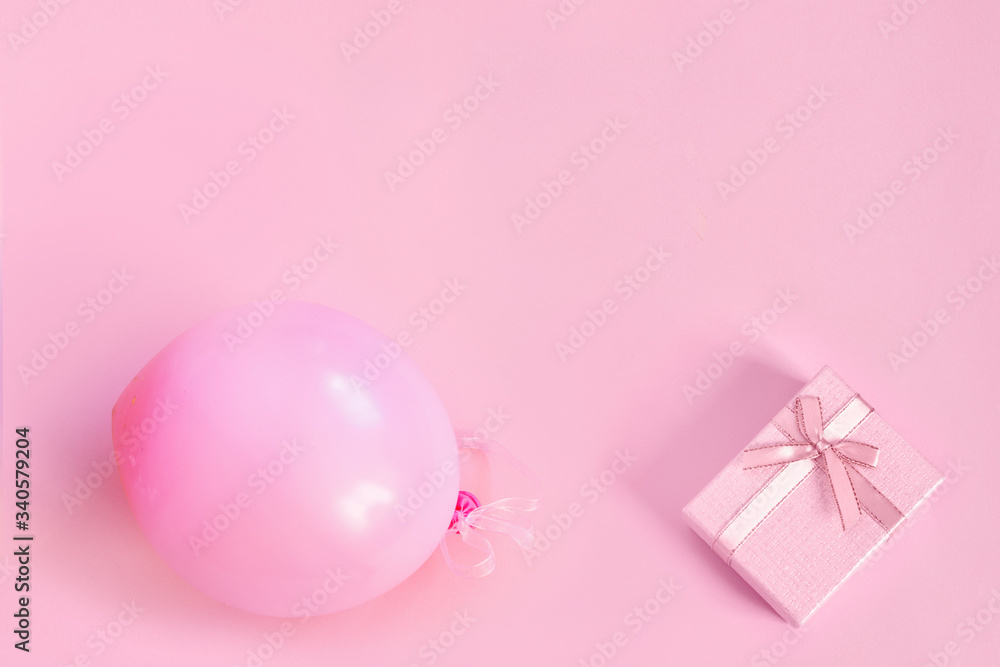 Pink ball and gift box with ribbon on paper background.