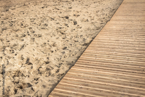 Boardwalk through the sand. Relax on the sandy beach. Holidays at sea. Walk in the fresh air. Sea air. Wooden path through the sandy beach. The texture of sand and boards.