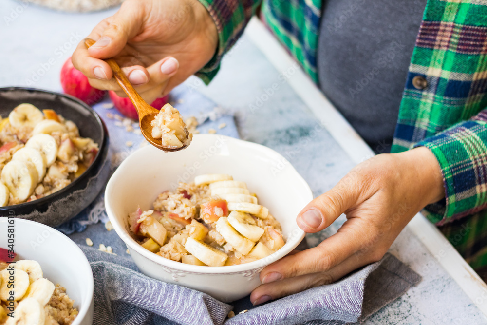 Oatmeal granola porridge with apple and banana fruits and nuts. Vegan healthy sweet breakfast. Woman hands