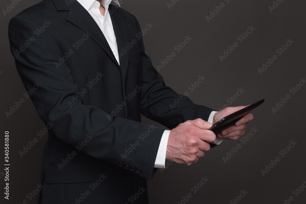 Businessman in black suit holding tablet pc in his hands closeup side view. Two hands holding device Businessman in black suit holding tablet pc in his hands closeup side view. Two hands holding device