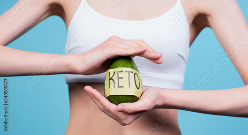 Cropped frame, the girl on the keto diet keeps the avocado.