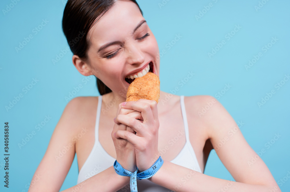 Young caucasian girl eating a croissant on a diet. Young caucasian girl eating a croissant on a diet.