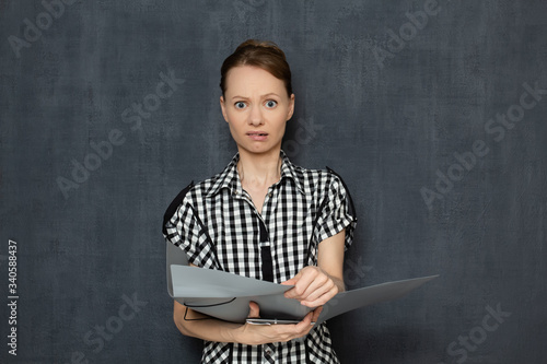 Portrait of upset perplexed woman holding open folder with documents