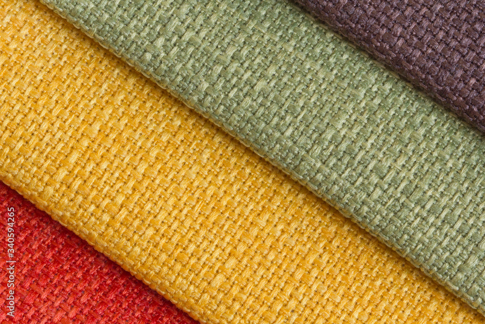 A set of colored samples of upholstery fabric for furniture in stock. Background from rolls of multi-colored fabric, empty template. Fabric Gun for furniture upholstery, green, yellow, red. A set of colored samples of upholstery fabric for furniture in stock. Background from rolls of multi-colored fabric, empty template. Fabric Gun for furniture upholstery, green, yellow, red.