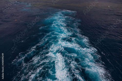 wake in blue water leaving port of Savona, Italy