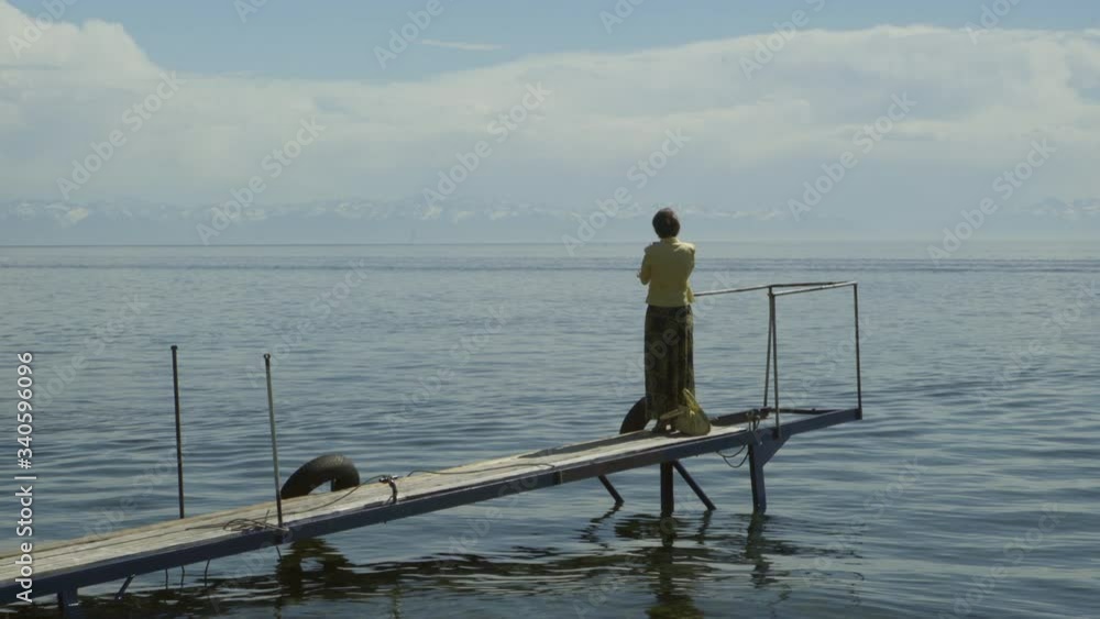 Lockdown: Lonely Woman Standing by the Old Wooden Docks Looking at the Vast Lake Towards the Mountains - Lake Baikal, Russia