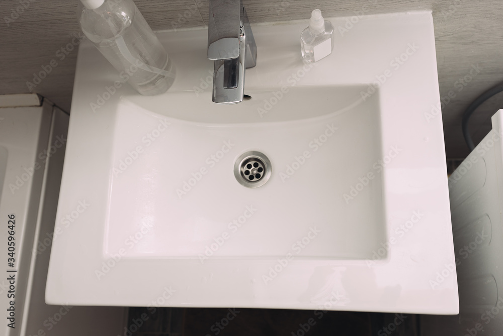 Fototapeta premium white sink in the bathroom, pandemic hand disinfection, carpet 19, disinfectant, soap and tap