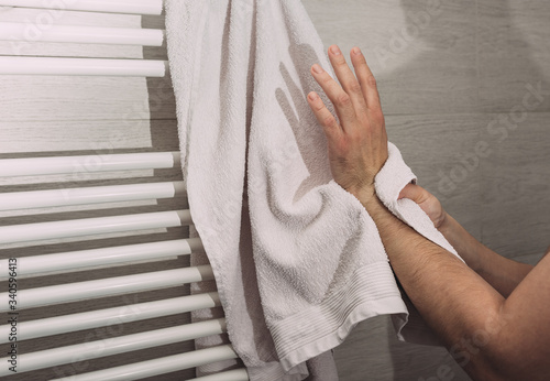 Person using towel for wiping hands dry after washing in bathroom at home. Hygiene and hand care. Keeping your hands clean during a Covid-19 coronavirus pandemic