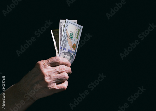 Dollars in the hands of an old woman on a black background. Money in the hands of an old woman.