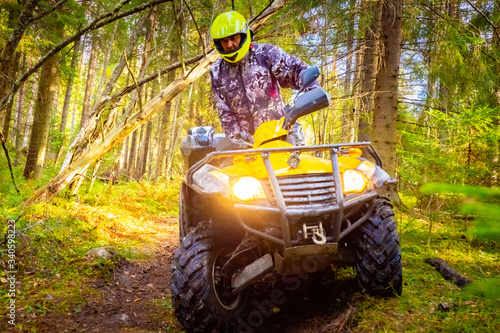 ATV in the forest close-up. Biker sits on an ATV. Man on a yellow ATV. Concept - orienteering in the forest. Off-road. Extreme Concept - Quadrocycle driving training. Race in the forest