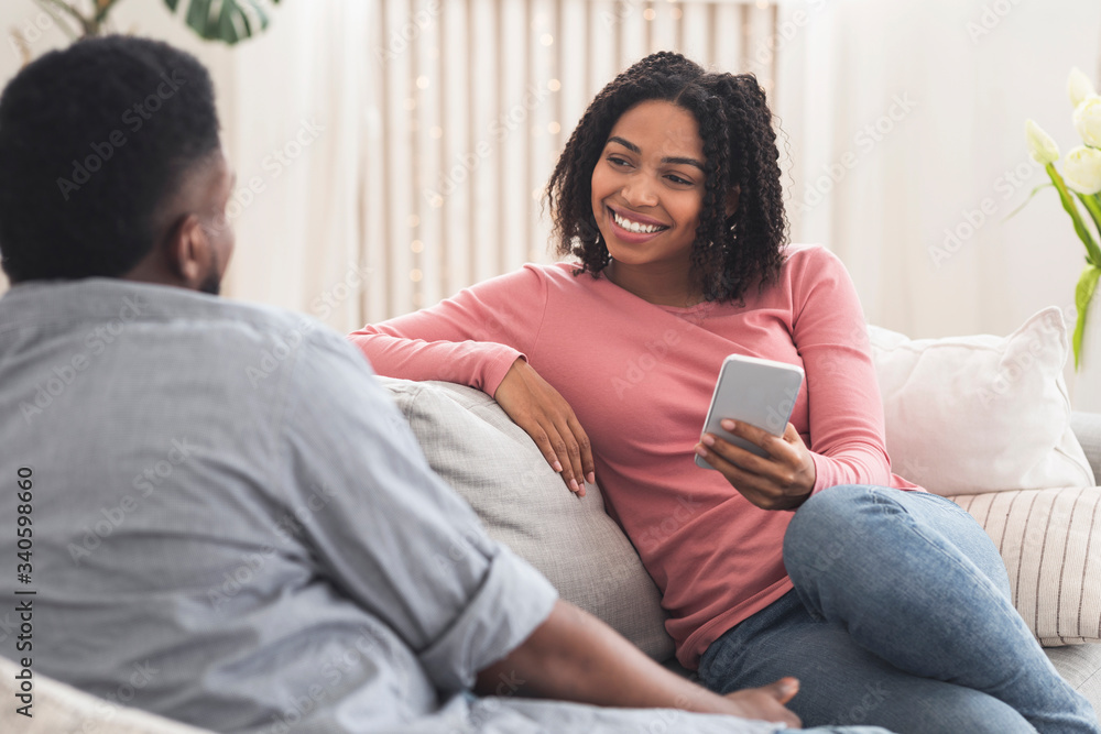 Young african couple chatting at home, relaxing on sofa together