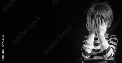 Quadro su tela Little Caucasians blond boy child 3-4 years old covered his face with his hands alone in the dark and is afraid