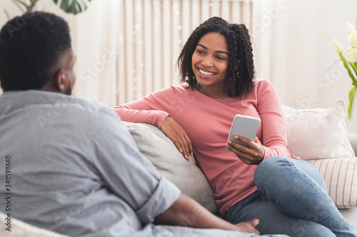 Young african couple chatting at home  relaxing on sofa together