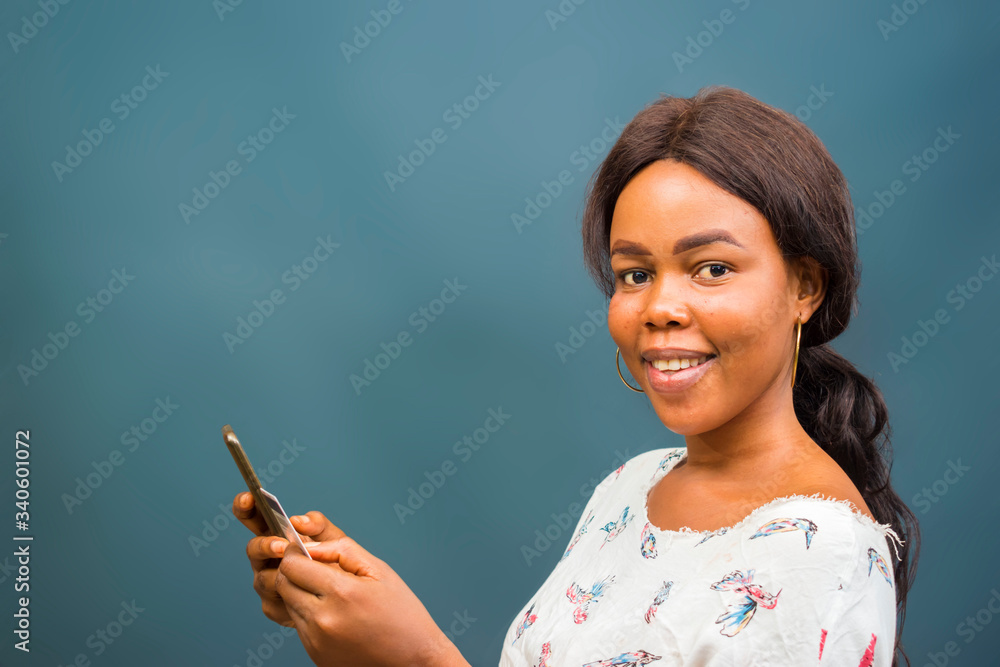 Obraz premium young beautiful african lady feeling excited about the transaction she carried out her cellphone, mobile phone, phone and holding her credit card