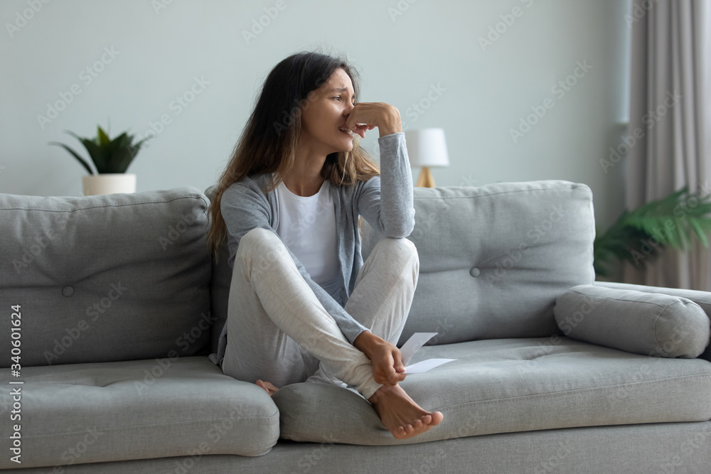 Depressed young woman suffering from break up with boyfriend or divorce with husband, holding torn photo, bad relationship, stressed upset girl crying, feeling lonely, sitting on couch at home alone Depressed young woman suffering from break up with boyfriend or divorce with husband, holding torn photo, bad relationship, stressed upset girl crying, feeling lonely, sitting on couch at home alone