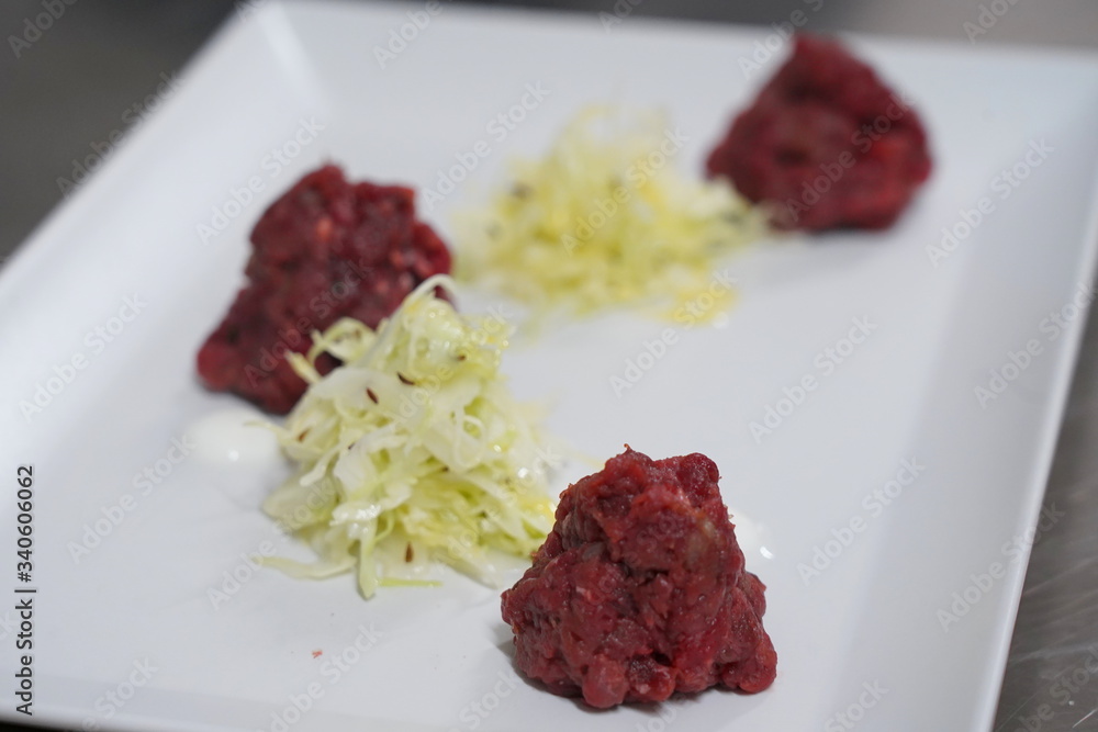 Beef tar-tar. Meat tar tar On a white plate, on a white background. a dish from a restaurant Beef tar-tar. Meat tar tar On a white plate, on a white background. a dish from a restaurant