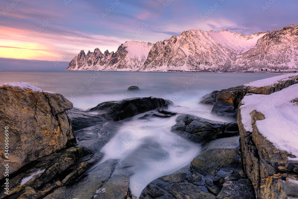 The rocky beach and pools at sunset on Ersfjord. Senja island in the Troms region of northern Norway. Long exposure shot