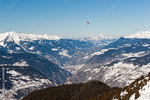 Panoramic view down a mountain valley with paragliders