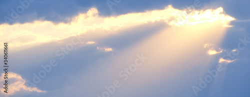 Tableau sur toile The sun's rays break through the blue clouds