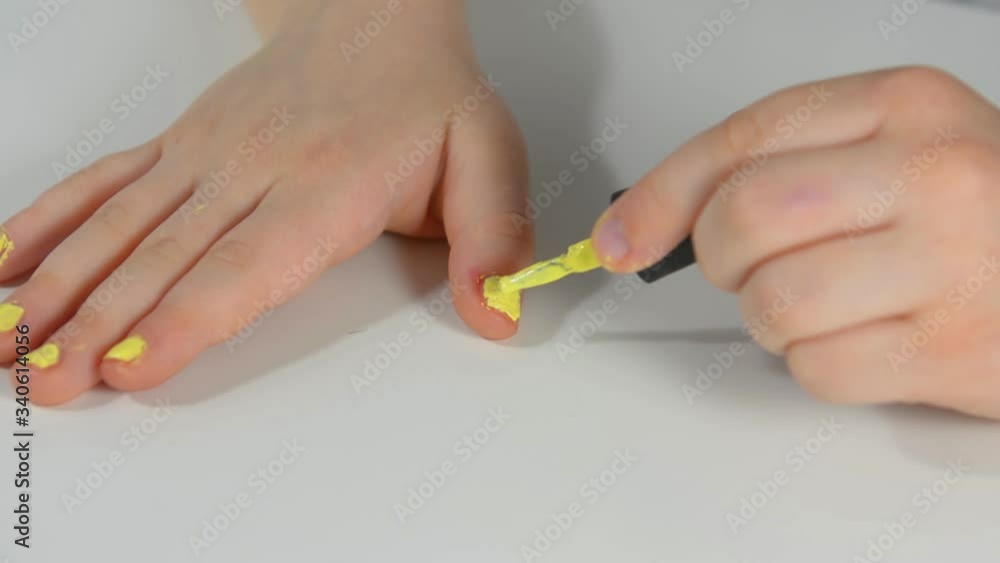 Little girl child paints nails. Girl paints nails in yellow. Small nails on a manicure. Funny paints nails. Bad manicure Little girl child paints nails. Girl paints nails in yellow. Small nails on a manicure. Funny paints nails. Bad manicure