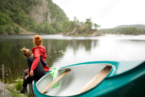 mother and daughter sitting on kayak by lake