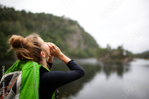 behind girl shouting by lake with hands to mouth