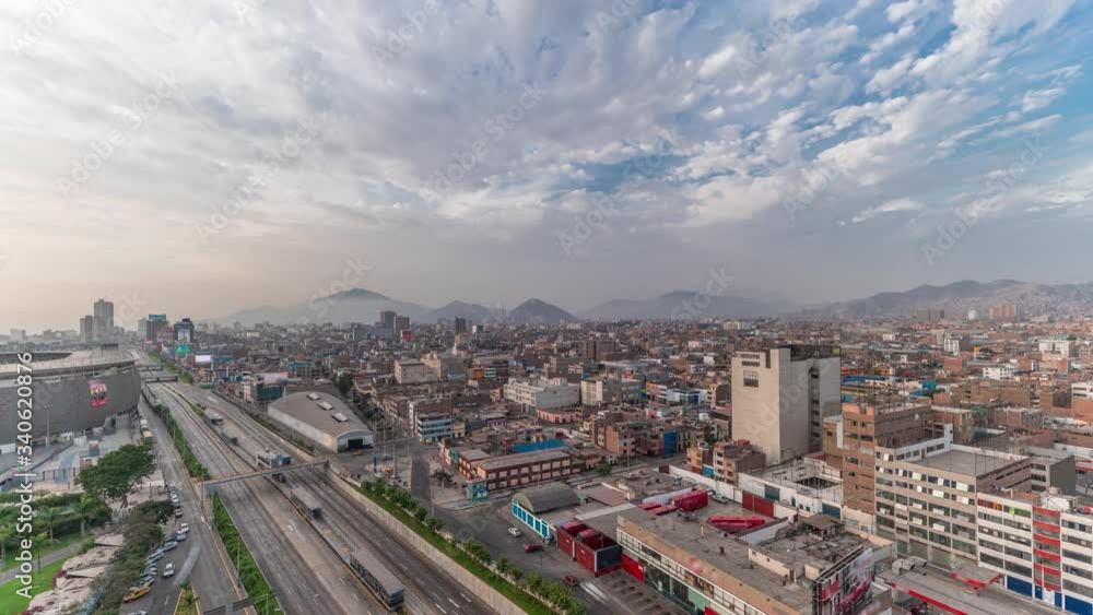 Aerial panoramic view of Via Expresa highway and metropolitan bus with traffic timelapse near National Stadium of Peru. Houses and city skyline with mountains on a background. Lima, Peru
