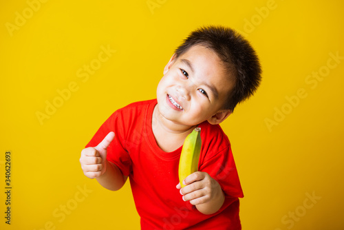 kid cute little boy attractive smile playing holds bananas and show finger thumb for good sign © sorapop