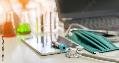 Selective focus of Doctor   s work space with Medical equipment  Stethoscope  Medical face mask  Vaccine  tablet and laptop Novel Coronavirus or Covid-19 pandemic concept.